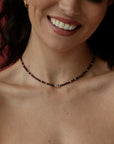 Close-up of a woman wearing a beaded necklace with a visible evil eye symbol.