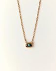 Aura Evil Eye necklace with a turquoise gemstone set in a gold plated pendant on a fine chain, styled as a luxury protective talisman.
