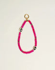 Close-up of Stella Bag Charm in Pink – A luxurious bag charm featuring vibrant pink quartz beads, 14k gold-plated charms, and a zirconia diamond Evil Eye charm for a bold, elegant look.
