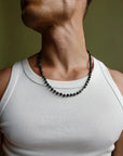 A man wearing the David Wrap in Silver as a necklace over a white tank top, highlighting the silver finish and dual evil eye charms with black CZ diamonds.