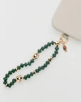 MyAleph Flat Hamsa evil eye charm styled with emerald phone charm strap, gold protective hand pendant with red enamel eye