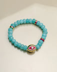 Close-up view of a single Leah turquoise bracelet, highlighting its striking blue-green beads, pink and gold accents, and a central eye charm.