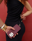 Full-body image of model styled in black, showcasing the Leah Phone Charm in Sapphire quartz with bold gold accessories.