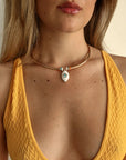 Model wearing the necklace styled with a yellow ribbed top, showing how the blue charm pops against a warm-toned outfit.