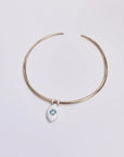 Overhead image of the necklace laid flat, highlighting the clean contrast of the gold and white dividers with the blue charm.