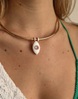 Close-up of the necklace worn with a green strap bikini top, highlighting the pink charm centered at the collarbone.