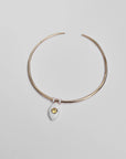 Overhead image of the necklace laid flat, highlighting the yellow CZ crystal and gold-accented dividers.