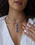 Woman wearing a silver choker necklace with blue evil eye pendants