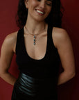 Woman wearing a black sleeveless top with a Mayra Evil Eye Choker necklace against a red background