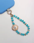 Aqua Quartz Mini India phone charm with Evil Eye Sun Charm and 14k Gold-Plated Hardware – Flat Lay on White Background with Blue Phone Case