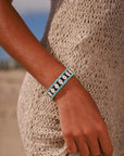 MyAleph Riviera Bracelet in Capri — navy and turquoise evil eye protective charm bracelet worn on wrist, styled with a cream knit summer dress on the beach.