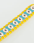 Close-up of MyAleph Riviera Bracelet with yellow cotton cord, turquoise enamel evil eye details, and adjustable clasp