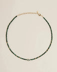 Flatlay of the Juliana Necklace in Malachite, showcasing deep green malachite beads and gold-plated adjustable clasp.
