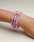 A set of three valerie lavender bracelets worn on the wrist, featuring soft purple beads with pink and gold accent dividers, offering a stylish, layered look.