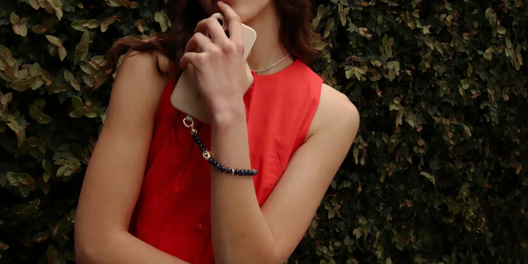 Model holding a smartphone styled with a MyAleph gemstone phone charm, worn like jewelry for an elegant, fashion-forward look.