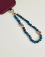 Close-up of Leah apatite phone charm with blue apatite beads, red accents, and gold evil eye charms attached to phone case