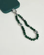 Close-up of Leah phone charm in emerald quartz with silver evil eye charms attached to a green phone case