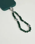 Close-up of Leah phone charm in emerald quartz with silver evil eye charms attached to a green phone case