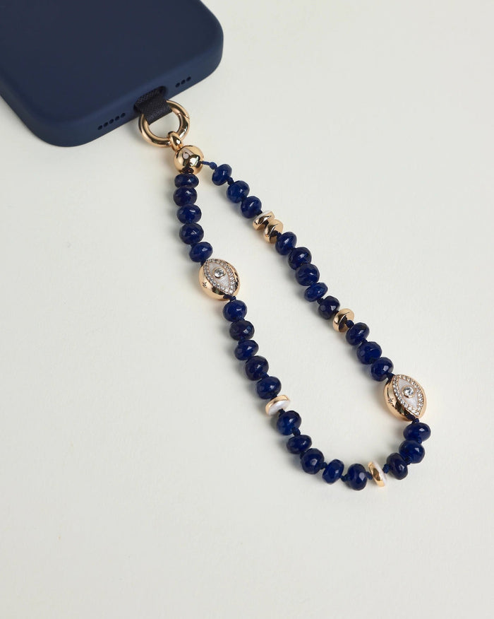 Close-up of Leah sapphire phone charm with deep blue beads, gold accents, and evil eye charms attached to a navy phone case