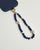 Close-up of Leah sapphire phone charm with deep blue beads, gold accents, and evil eye charms attached to a navy phone case