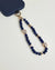 Close-up of Leah sapphire phone charm with deep blue beads, gold accents, and evil eye charms attached to a navy phone case