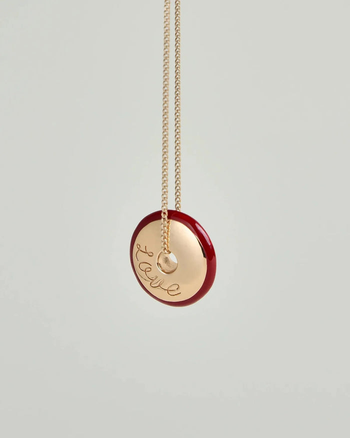 Love Necklace by MyAleph, gold disc charm with red enamel border and love script engraving, front detail view