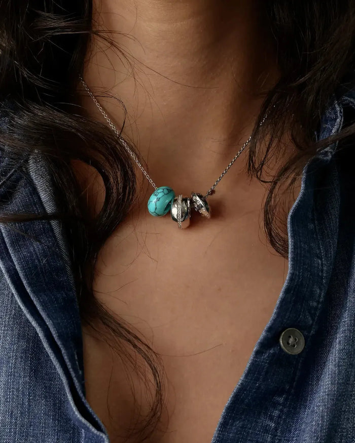 Noa silver charm necklace with turquoise quartz bead and diamond-detailed charms styled with a denim shirt by MyAleph