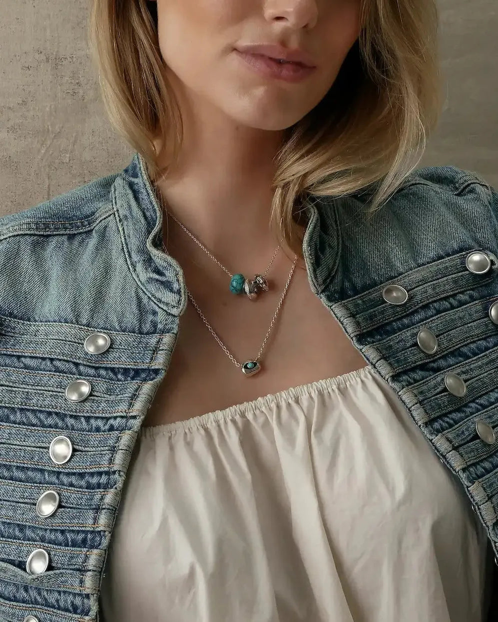 Model wearing the Noa Silver Necklace with a turquoise quartz bead and silver-toned charms, styled with a light-wash denim jacket and cream top.