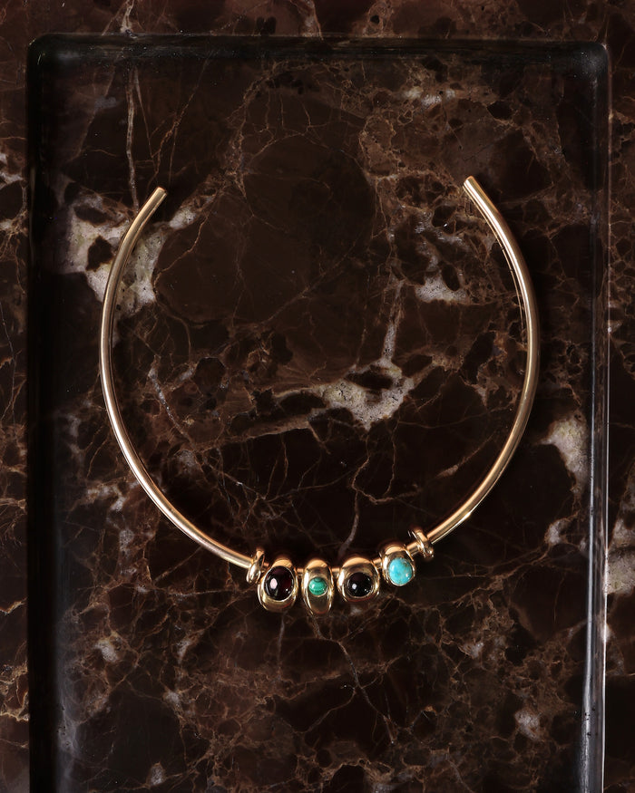 Terre gold choker necklace with turquoise, garnet and onyx charms on model in black top