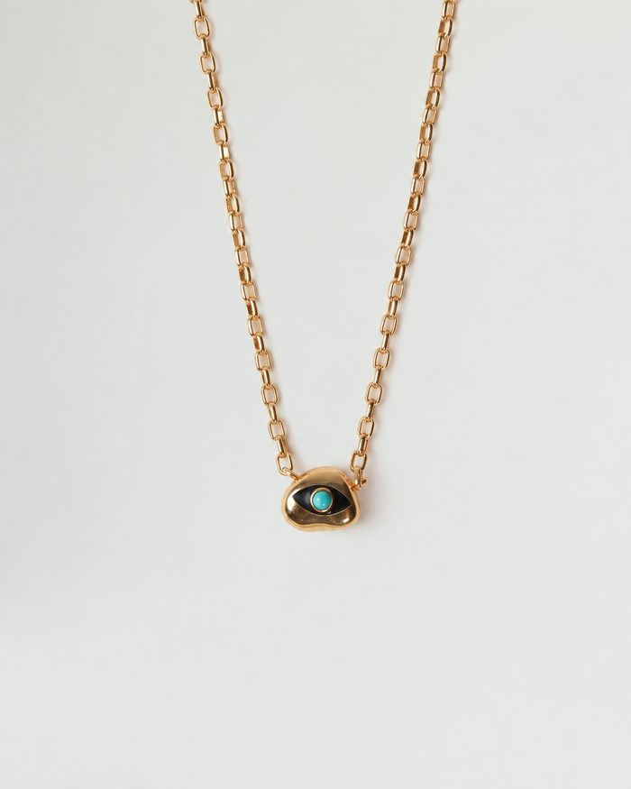 Aura Evil Eye necklace with a turquoise gemstone set in a gold plated pendant on a fine chain, styled as a protective talisman.