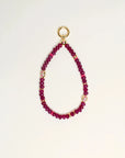 Close-up of Leah Bag Charm in Amethyst – A faceted amethyst quartz bag charm adorned with 14k gold-plated details and Evil Eye charms, designed for cleansing and well-being.