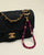 Leah Bag Charm in Amethyst attached to a quilted denim Chanel bag – A faceted amethyst quartz bag charm with 18K gold-plated accents and Evil Eye charms clipped onto a refined quilted denim Chanel handbag, highlighting its elegant and protective design.