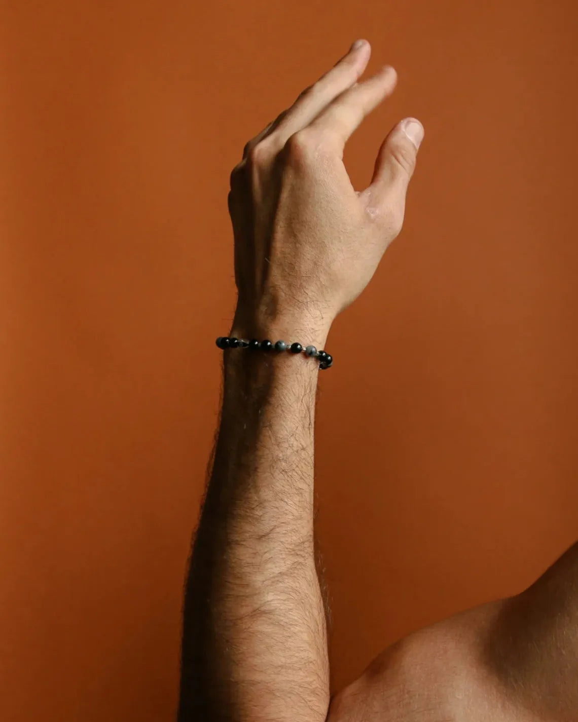 A close-up shot of a man extending his arm while wearing the David Bracelet in Silver, highlighting the bracelet’s refined silver finish and bold black stones.