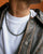 A man wearing the David Wrap in 18K Gold as a necklace, styled with a leather jacket for a modern, bold look.