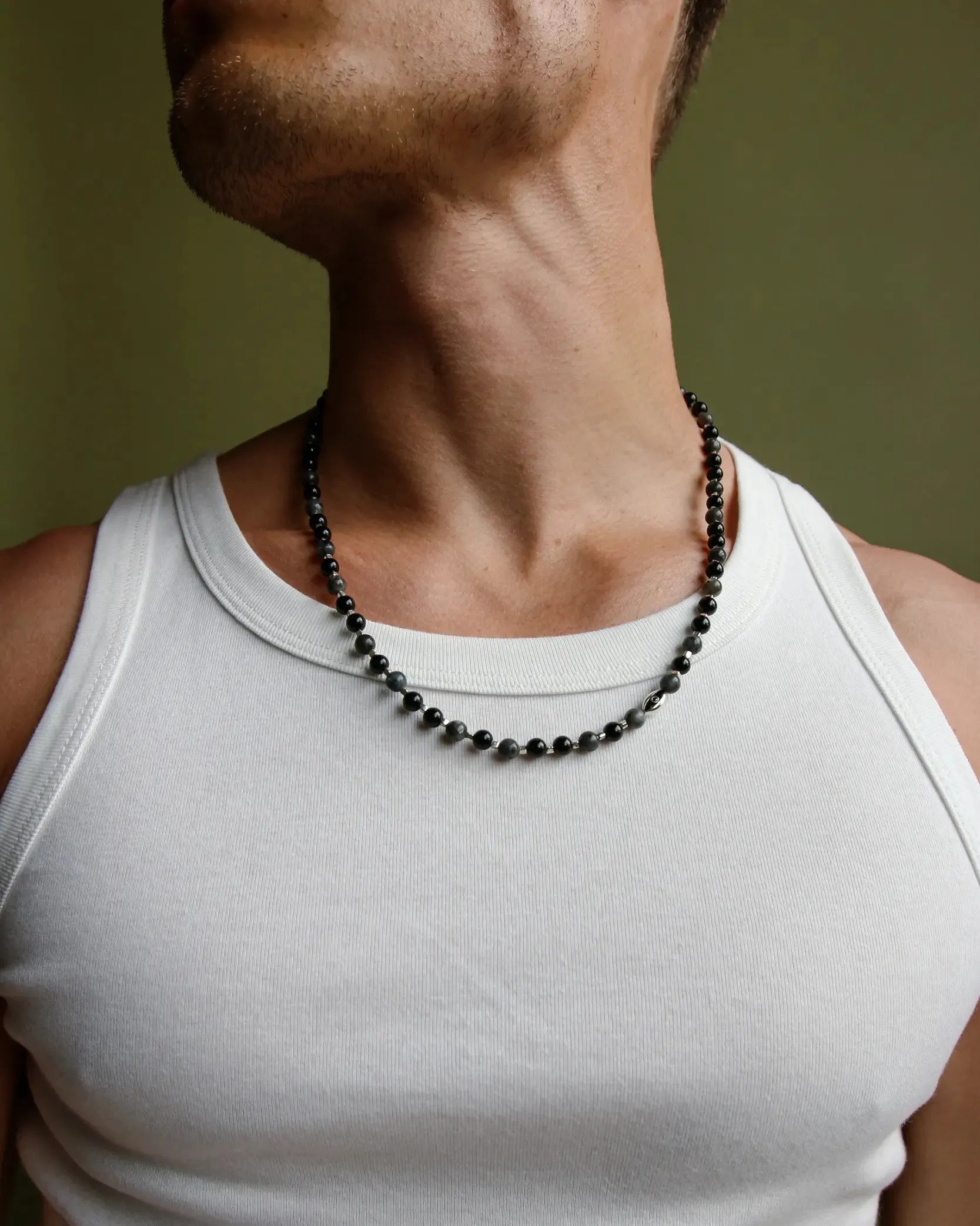 A man wearing the David Wrap in Silver as a necklace over a white tank top, highlighting the silver finish and dual evil eye charms with black CZ diamonds.