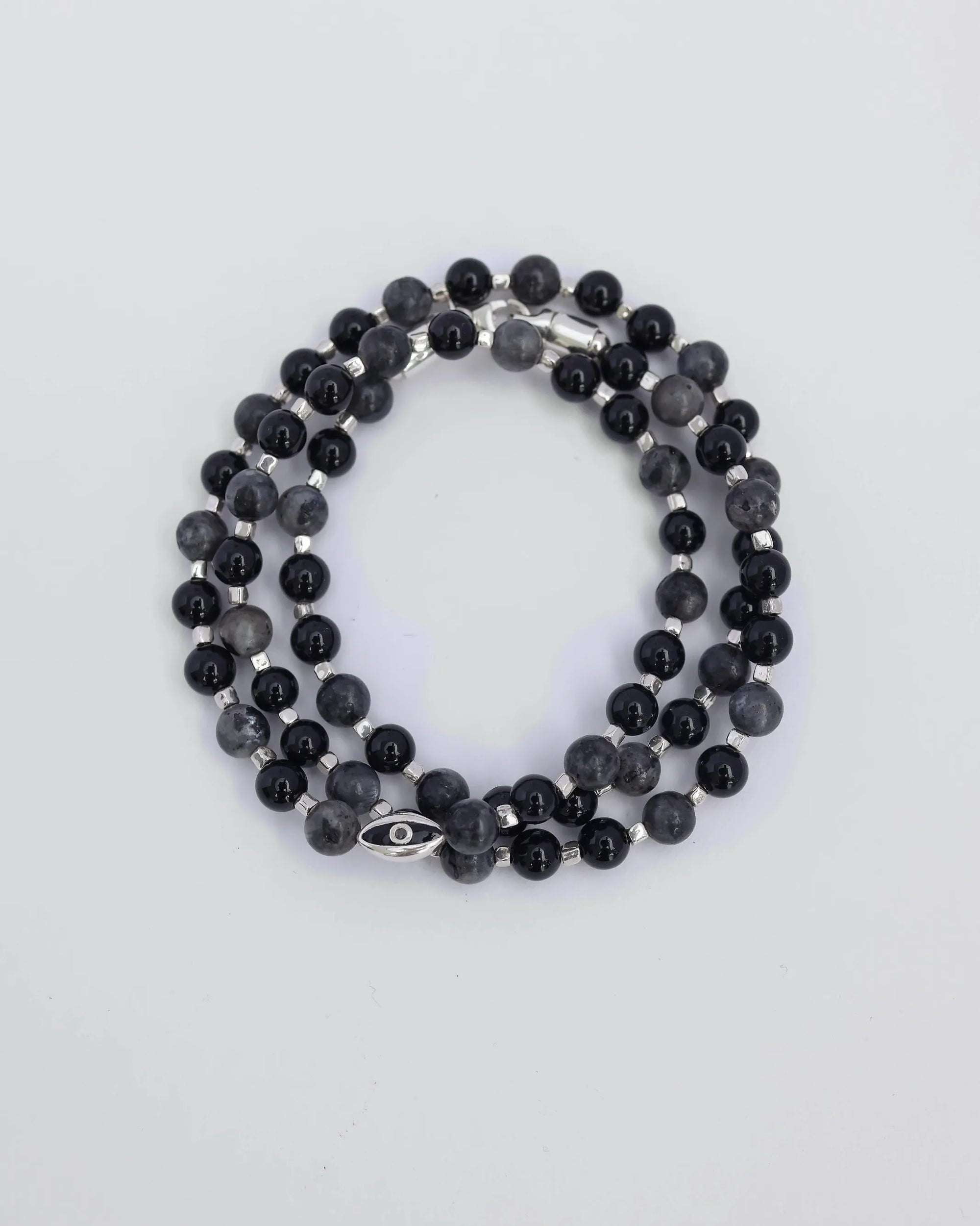 The David Wrap in Silver laid flat and wrapped, showcasing its polished silver finish, 6mm black onyx and black labradorite quartz beads, and dual evil eye charms.