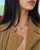 Model wearing the Eden Necklace with a Blue Topaz Gemstone and a tan suede jacket