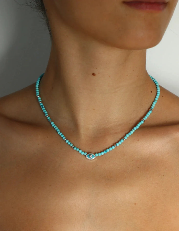 Turquoise evil eye necklace with silver accents worn on model