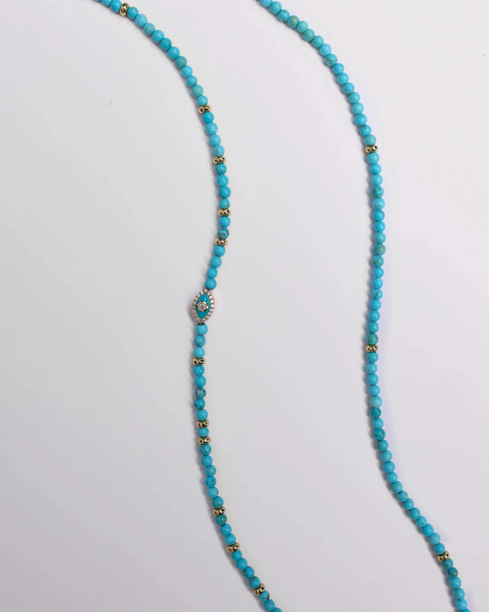 Turquoise beaded belly chain with gold accent beads and a central evil eye charm, laid out on a white background.