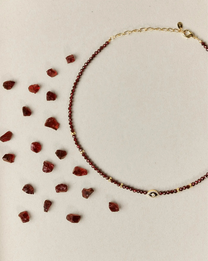 Garnet necklace with scattered gemstones on a beige background