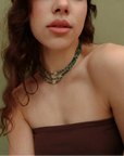 Model wearing the Juliana Necklace in Malachite with a strapless brown top, highlighting the bold green beads and evil eye charm.