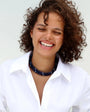 model smiling wearing a white collar shirt accessorised in sapphire beaded lilou necklaces
