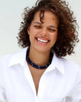 model smiling wearing a white collar shirt accessorised in sapphire beaded lilou necklaces