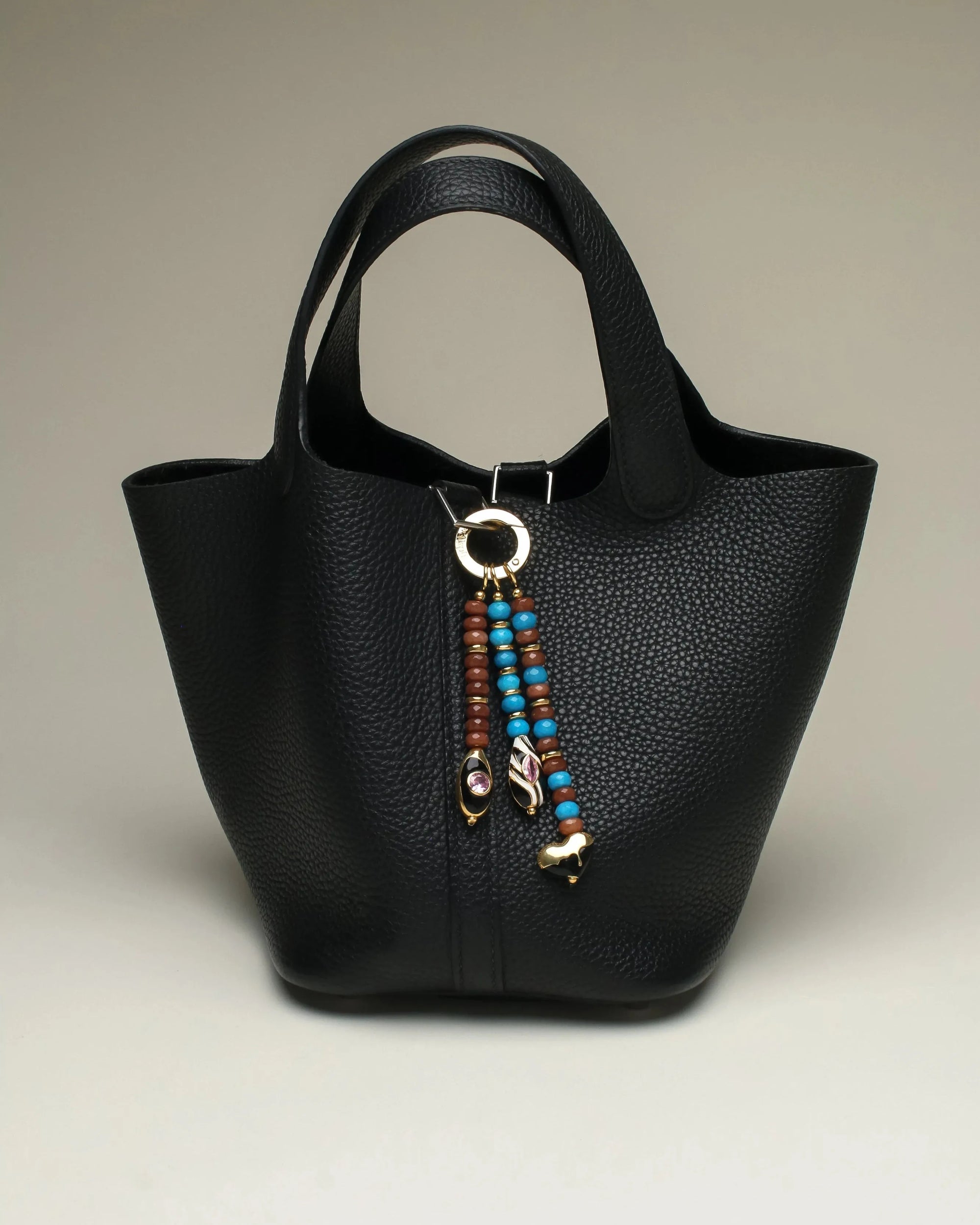 The Liora Bag Charm in Azure &amp; Espresso styled on a sleek black tote bag, showcasing its versatility and chic design.