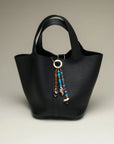 The Liora Bag Charm in Azure & Espresso styled on a sleek black tote bag, showcasing its versatility and chic design.
