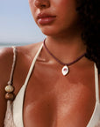 Model wearing MyAleph Lola Cord Necklace in Sunset with bordeaux cord and rose evil eye pendant in a summer beach look