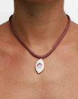 Model wearing MyAleph Lola Cord Necklace in Sunset with bordeaux cord, rose evil eye pendant, and white stone detail
