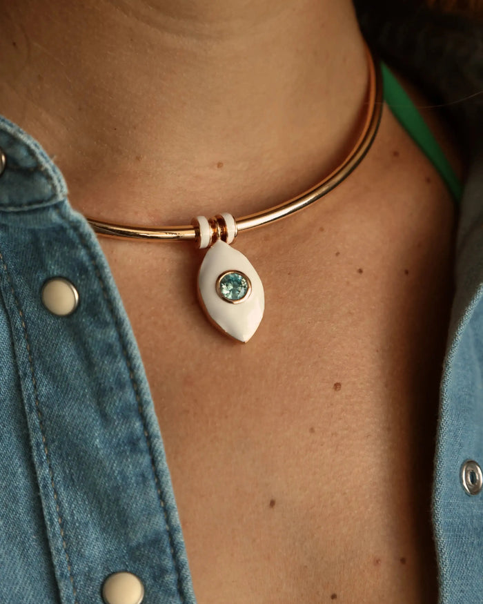 Close-up of the necklace worn with a denim top, showcasing the blue evil eye charm at the center of the collarbone.