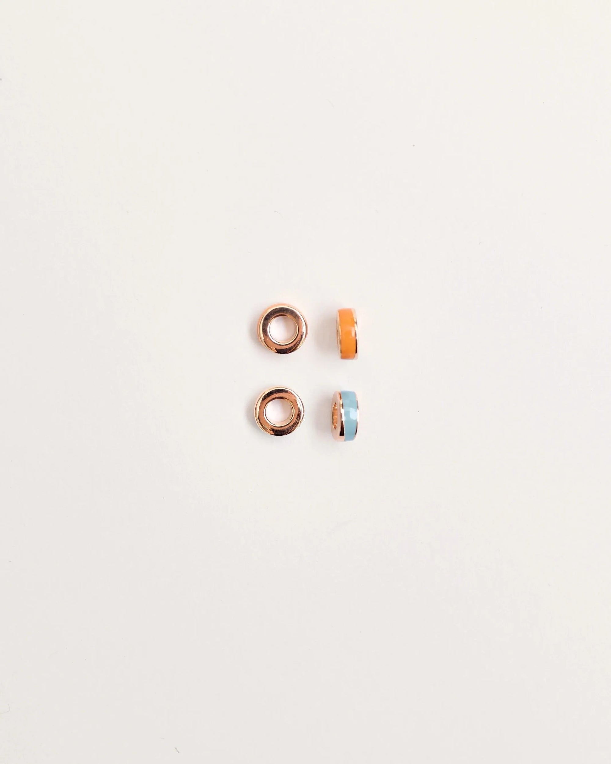 Set of four Lola Dividers featuring two gold-plated rings and two enamel rings in bold orange and cool blue, displayed on a white background.