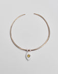 Gold collar necklace with a yellow ceramic evil eye charm and two white enamel dividers, displayed flat on a light background.